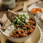 Enjoy a healthy vegan chickpea rice bowl garnished with fresh cucumbers and herbs, perfect for a nutritious dinner.